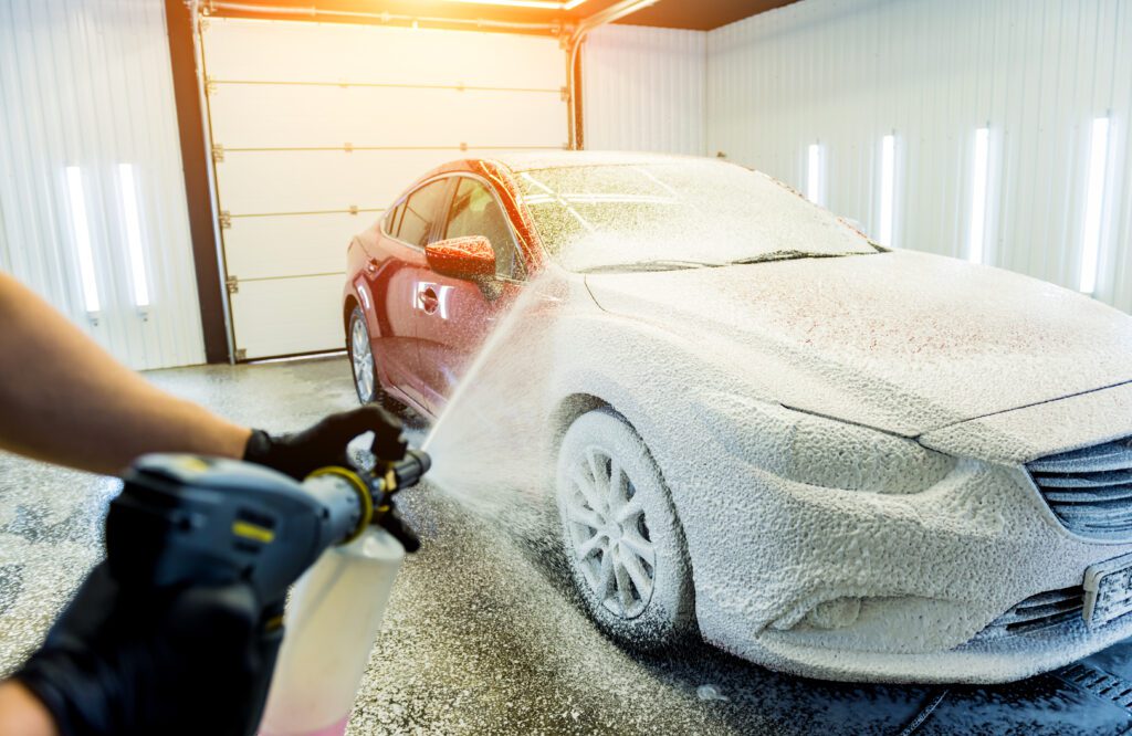 Snow foam being applied to a red car.