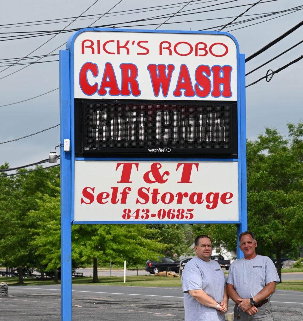 Rick and his mechanic in front of the Rick's Robo Car Wash Sign