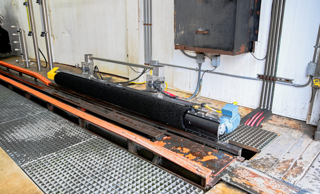Tire dressing applicator brush at the end of a car wash tunnel.